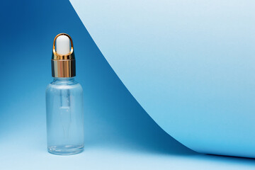 glass dropper bottle for serums, oils, lotions and cosmetic liquids on blue background