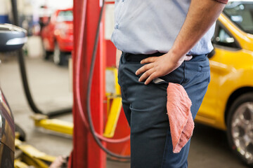 Torso of a mechanic with his hands on his hips in an auto repair shop