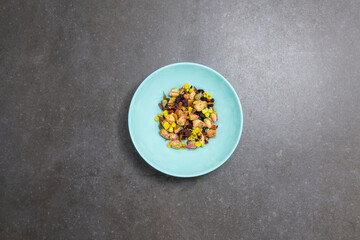 Flowers and other fruit tea ingredients in a blue plate on the dark, marble background. Top view. Copy space. 