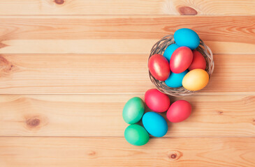 Obraz na płótnie Canvas Colorful easter eggs in wicker basket on wooden background.