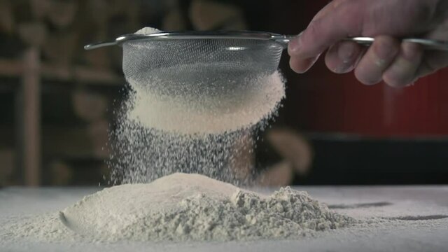 The hand of a young man holding a sieve for flour or powdered sugar. Through which sift products for baking bread, rolls, cakes and pizza