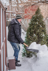 Snow collapse, man cleaning snow at winter weather with a shovel on a yard, winter trouble concept