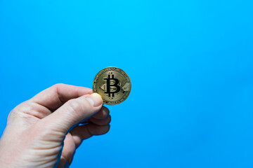 Fototapeta na wymiar hand of an adult holds bitcoin coin. bitcoin cryptocurrency on blue background