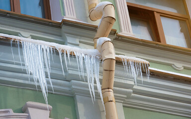 Icicles on the eaves of building, poor insulation of building is the reason for appearance of...