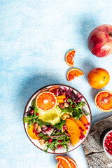 Clean healthy eating concept. Buddha bowl with avocado, blood orange, broccoli, watermelon radish, spinach, quinoa, pumpkin seeds on a blue background. vertical image, place for text