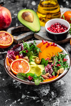 Buddha bowl with avocado, blood orange, broccoli, watermelon radish, spinach, quinoa, pumpkin seeds on a dark background. vertical image, place for text