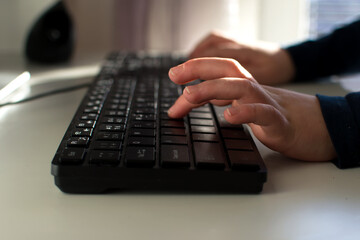kids hands typing on keyboard in front of desk computer. Kid, communication and technology concept.
