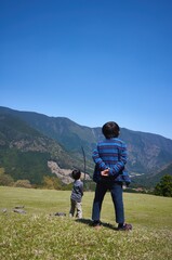 Fototapeta na wymiar 自然豊かな爽やかな高原でハイキングやアウトドアスポーツを楽しむ子ども達