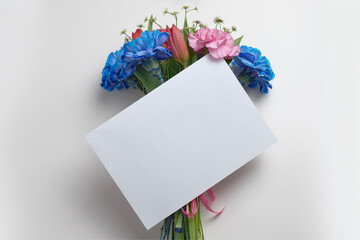 White business card mockup with a beautiful bouquet of flowers on a gray, beige table. A4 format