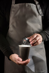 The barista is holding a glass of hot coffee.