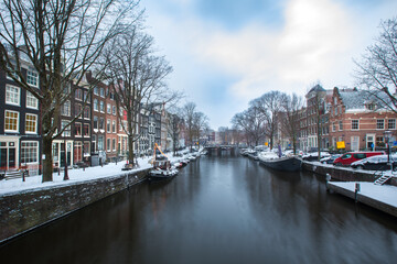Winter snow view of Dutch canal and old houses in the historic city of Amsterdam, the Netherlands