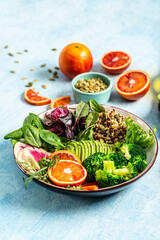 Vegan, detox Buddha bowl with vegetables, avocado, blood orange, broccoli, watermelon radish, spinach, quinoa, pumpkin seeds. Balanced food. Delicious detox diet. Top view. vertical image