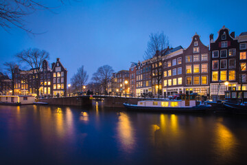 Fototapeta na wymiar Winter snow night view of Dutch canal and old houses in the historic city of Amsterdam, the Netherlands