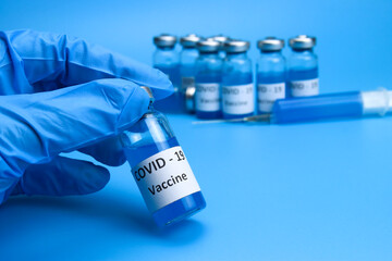The doctor holds a coronavirus vaccine in hand on a blue background. The concept of the fight against ncov COVID-19 pandemic
