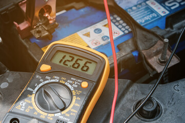 Mechanicl man uses electric multimeter voltmeter to check the voltage level