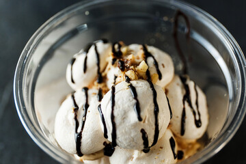 Dessert of egg white, meringue, meringue with nut crumbs and chocolate sauce in a transparent plastic glass