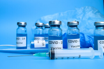 Ampoules with coronavirus vaccine and a syringe on a blue background. The concept of the fight against ncov COVID-19 pandemic