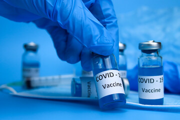 The doctor holds a coronavirus vaccine in hand on a blue background. The concept of the fight against ncov COVID-19 pandemic