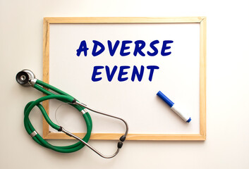 The text ADVERSE EVENT is written on a white office board. Nearby is a stethoscope.