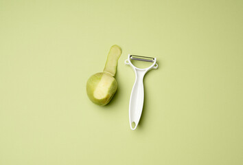 plastic knife for peeling vegetables and fruits and a green apple on a green background
