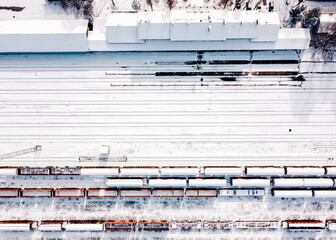 Top view of cargo trains and railway station. Aerial top view from flying drone of snow covered freight trains on the railway station.