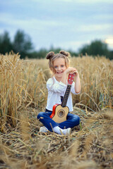 Naklejka na ściany i meble beautiful girl with a guitar in a field with wheat in summer.