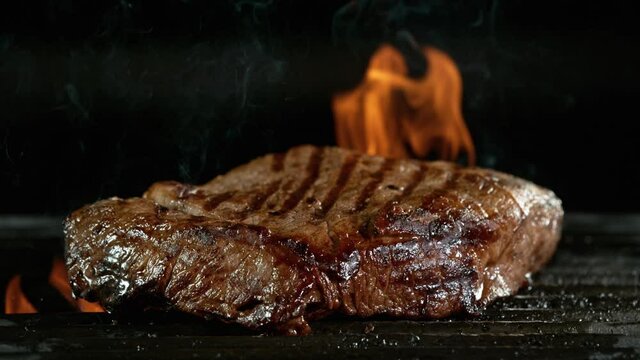 Close-up of tasty beef steak on iron cast grate, super slow motion, filmed on high speed cinematic camera at 1000 fps.