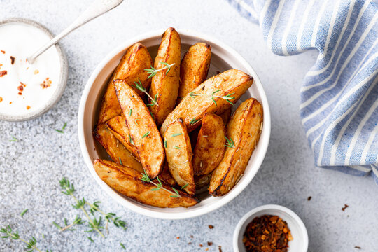 baked potato wedges with sauce on a light background, top view