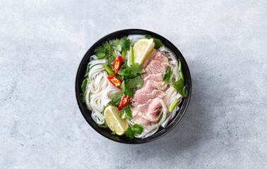 Pho Bo vietnamese soup with beef and rice noodles on a concrete background, top view