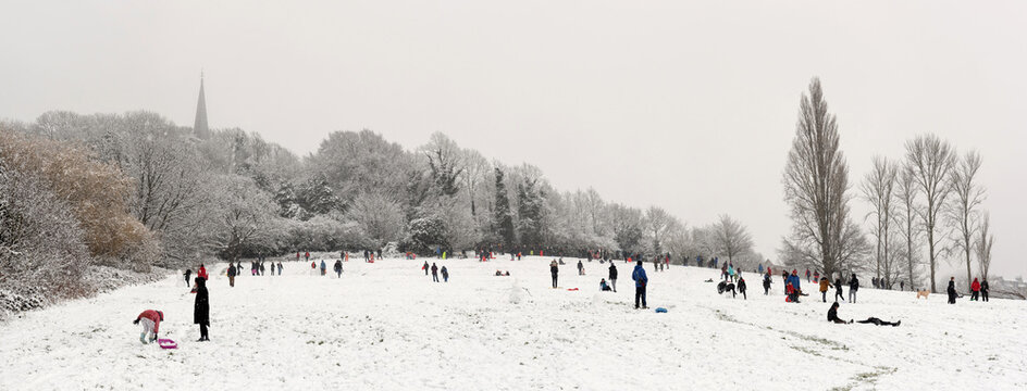 Crowd of people enjoying snow in Harrow on the Hill, England 