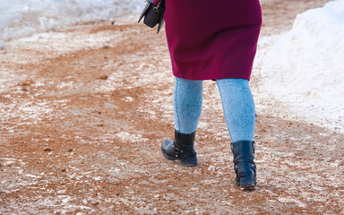 Woman walking on snowy sidewalk spreading with sand, prevention of pedestrians injury. Road service...