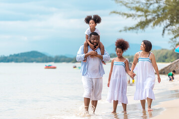 Happy African American family with African American father / asian mother and mixed race kids walking on the beach, thaliand