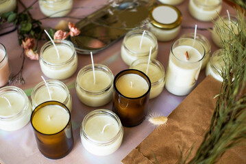 Soy Candles poured into recycled bottles and jars. Many soy wax candles together on store or workshop background. . Ecological and vegan business.