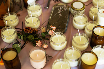 Soy Candles poured into recycled bottles and jars. Many soy wax candles together on store or workshop background. . Ecological and vegan business.