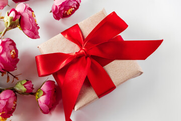 Gift box with red ribbon and flowers on a white background.