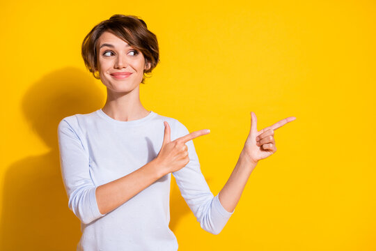 Photo portrait of woman pointing two fingers at blank space isolated on bright yellow colored background