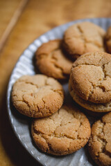 a delicious looking batch of snickerdoodle cookies and some warm milk in a rustic looking cup. the cookies are freshly baked and have   Cinnamon and sugar on them. the cow milk is fresh and warm. 