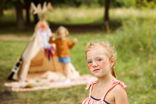 Portrait of a serious girl with native americans makeup on her face.