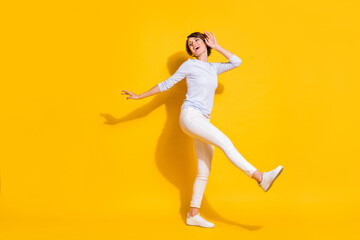 Fototapeta na wymiar Full length photo of funny adorable young woman wear white shirt dancing walking isolated yellow color background