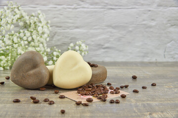 Fragrant coffee natural handmade soap in the shape of a heart and coffee beans on a wooden countertop.