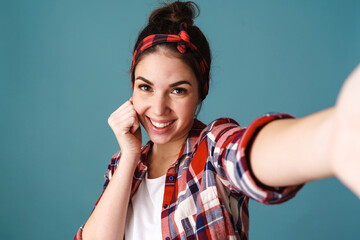 Joyful caucasian young woman smiling while taking selfie photo