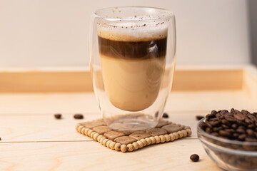 Coffee in a glass thermostat on a wooden tray. Wooden background with a cup of cappuccino and coffee beans