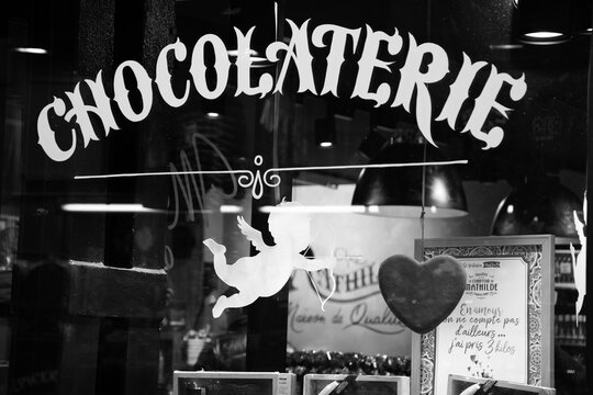 PARIS, FRANCE - FEBRUARY 14, 2019: Le Comptoir de Mathilde , known for its chocolats and gourmet products, decorated for Valentine day with two cupids and hearts. Black white historic photo.