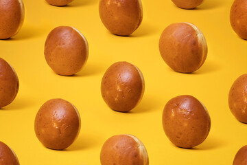 Colorful pattern with round burger bread buns with sesame seeds on yellow background