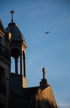 Billettes church in Paris (France) in golden sunset light rays. Flying bird in sky over cross.  Billettes church, nowadays protestant, has Paris&rsquo; last medieval cloister.