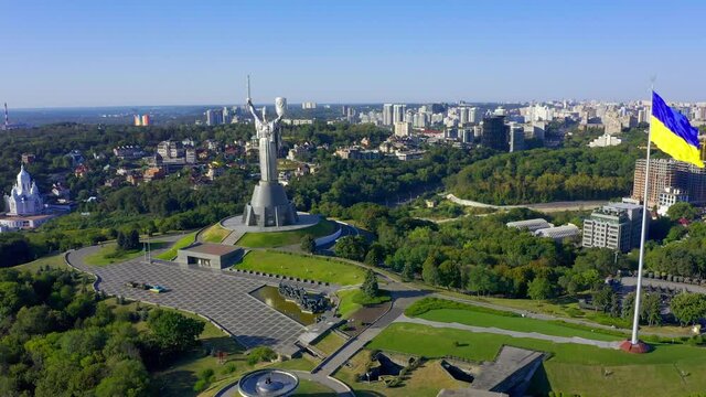 Flying a drone to the famous monument in Ukraine Motherland. Cinematic aerial view to the Motherland statue in the Kiev and national flag. Ukraine.  Monument of the Motherland in Kiev.
