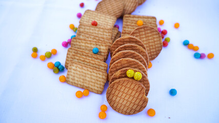 Wheat round biscuits with colorful jelly beans isolated on white background. Heap of brown Delicious Cookies known as Chai biscuit or tea biscuits
