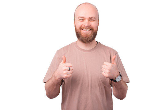 Photo of cheerful smiling bearded man showing thumbs up and looking at the camera over white background.