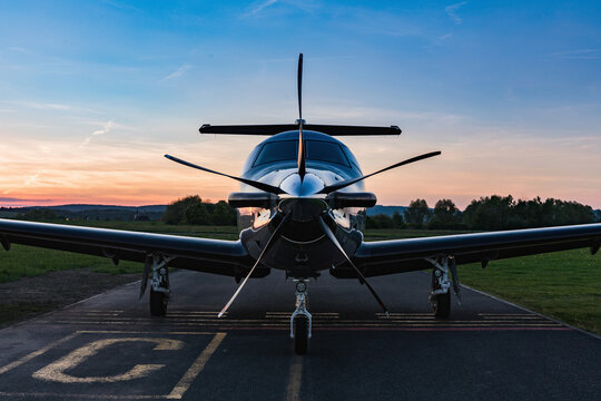 A single-engine plane is parked on the runway, bathed in the evening sun. Beautiful color view of the plane.