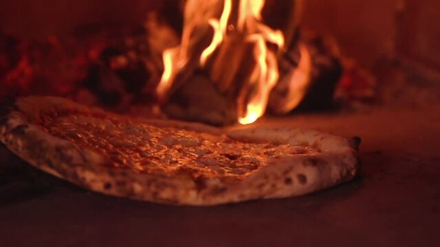The process of cooking the most delicious Italian pizza in a wood-fired oven with a flame on the background